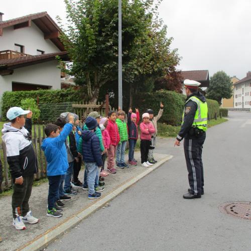 Kinder am Gehsteig mit Polizist
