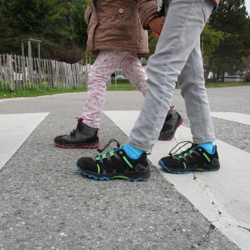 Kinderfüße überqueren den Zebrastreifen