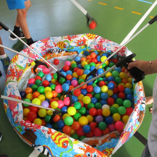 Kinder holen Bälle mit Greifarm aus Becken