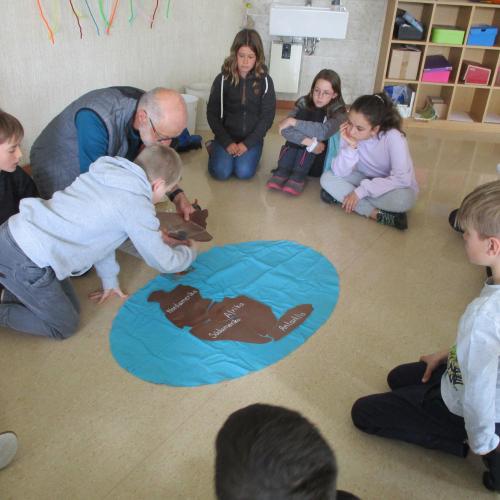 Kinder im Sitzkreis mit Modell der Kontinente