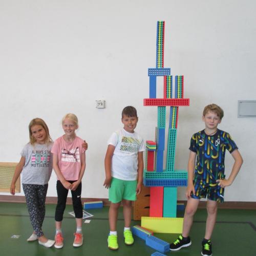 Kinder im Turnsaal neben Turm aus Bauklötzen