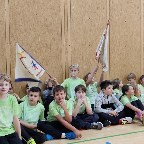 Kinder sitzen in der Sporthalle