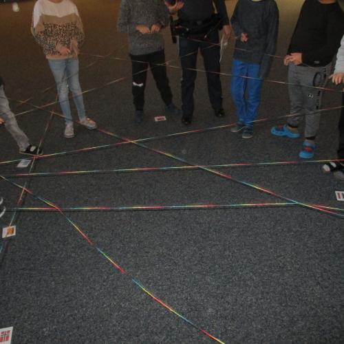 Kinder im Kreis, die einen Wollfaden als Spinnennetz halten