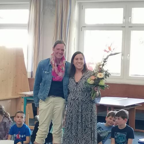 Direktorin übergibt Lehrerin zum Abschied einen Blumenstrauß